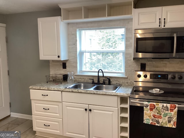 1141 N Clark St, Milledgeville, GA 31061 - kitchen featuring a sink, white cabinetry, light countertops, appliances with stainless steel finishes, and decorative backsplash