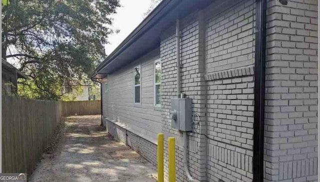 view of side of property featuring brick siding and fence