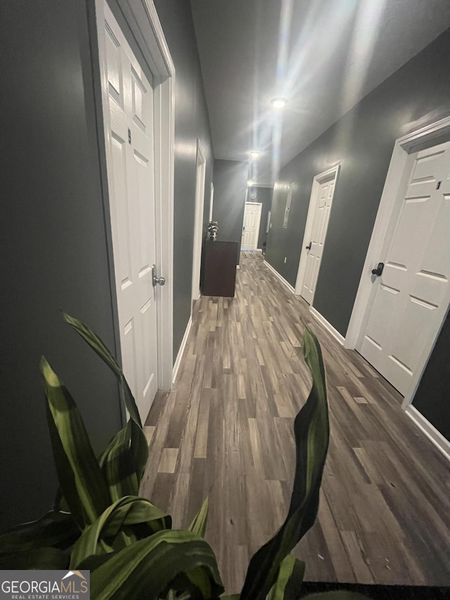 corridor with dark wood-style flooring and baseboards