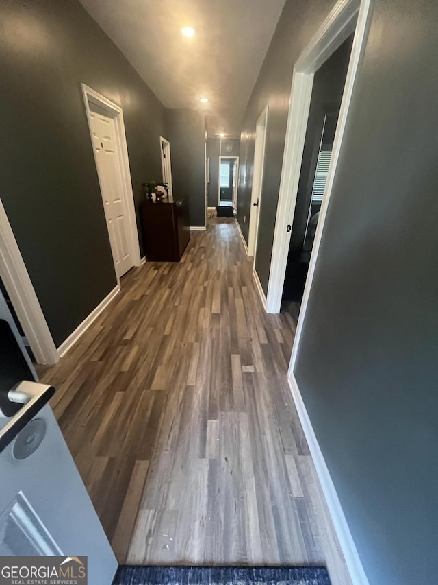 hall with dark wood-type flooring and baseboards