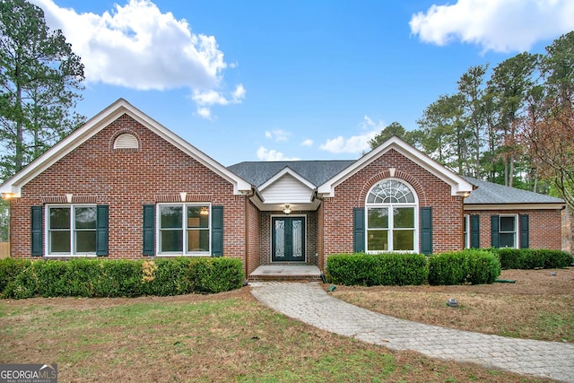 ranch-style home with a front lawn, french doors, and brick siding