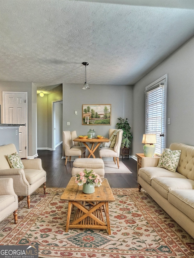 living room featuring a textured ceiling, baseboards, and wood finished floors