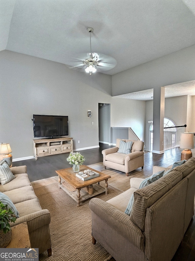 living area featuring lofted ceiling, ceiling fan, and baseboards