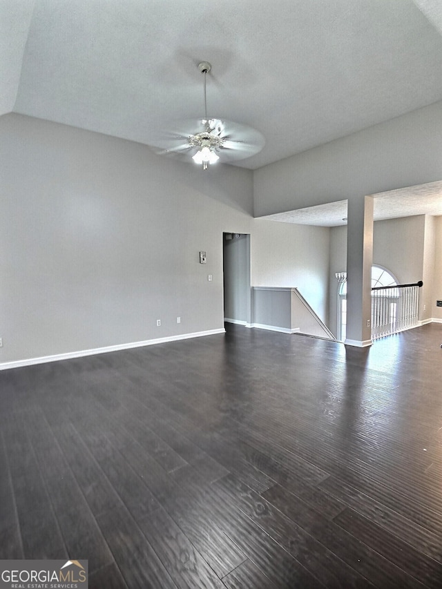 unfurnished living room featuring lofted ceiling, ceiling fan, baseboards, and dark wood finished floors