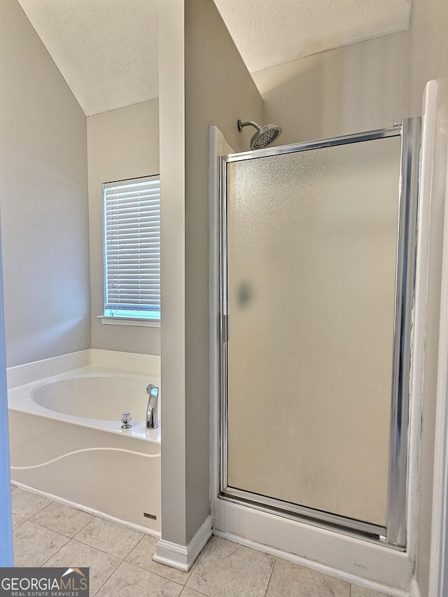 full bathroom featuring a bath, a stall shower, tile patterned flooring, and a textured ceiling