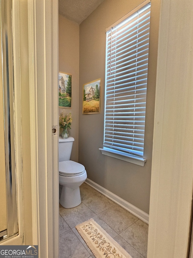 bathroom featuring tile patterned flooring, toilet, and baseboards