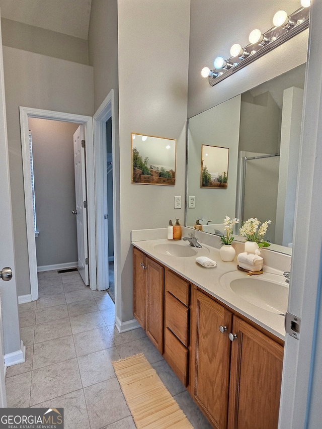 bathroom with double vanity, a sink, baseboards, and tile patterned floors