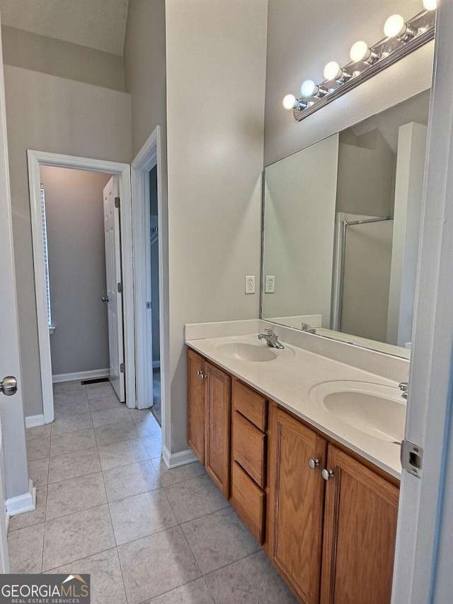 bathroom featuring baseboards, double vanity, a sink, and tile patterned floors