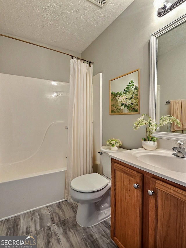 full bath with toilet, a textured ceiling, shower / bath combination with curtain, and vanity