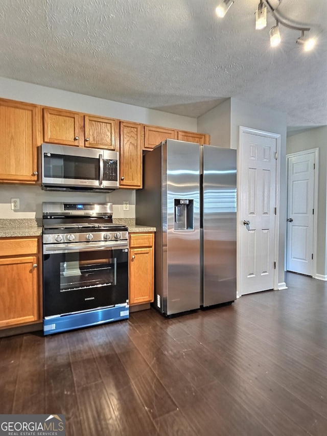 kitchen featuring appliances with stainless steel finishes, brown cabinets, light countertops, and dark wood-style floors