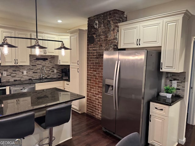 kitchen featuring stainless steel appliances, a sink, hanging light fixtures, backsplash, and dark wood-style floors