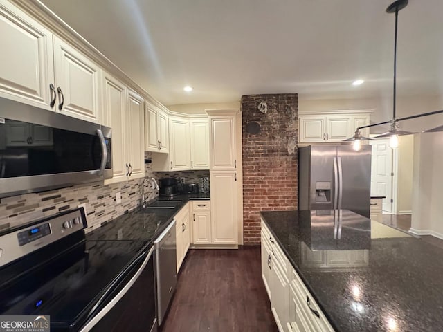 kitchen featuring pendant lighting, stainless steel appliances, tasteful backsplash, a sink, and dark stone countertops