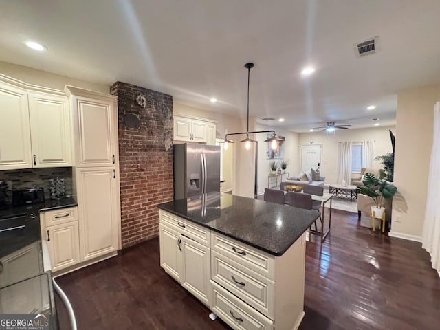 kitchen with stainless steel fridge, visible vents, dark wood finished floors, open floor plan, and a center island