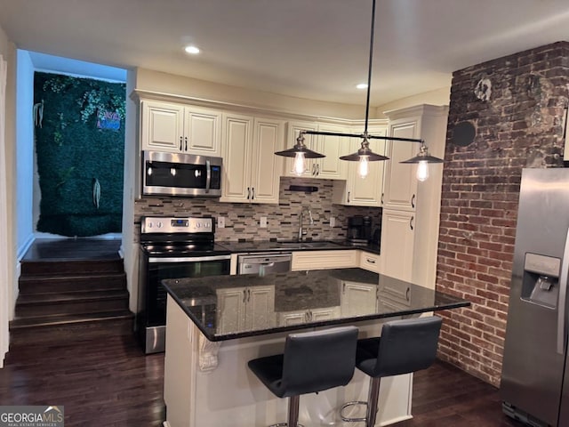 kitchen featuring dark stone countertops, a center island, dark wood-style flooring, a sink, and stainless steel appliances