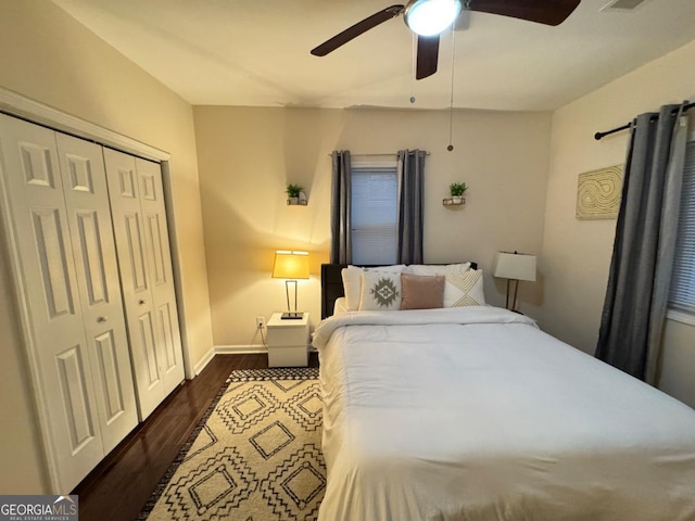 bedroom with dark wood-style flooring, a closet, visible vents, ceiling fan, and baseboards