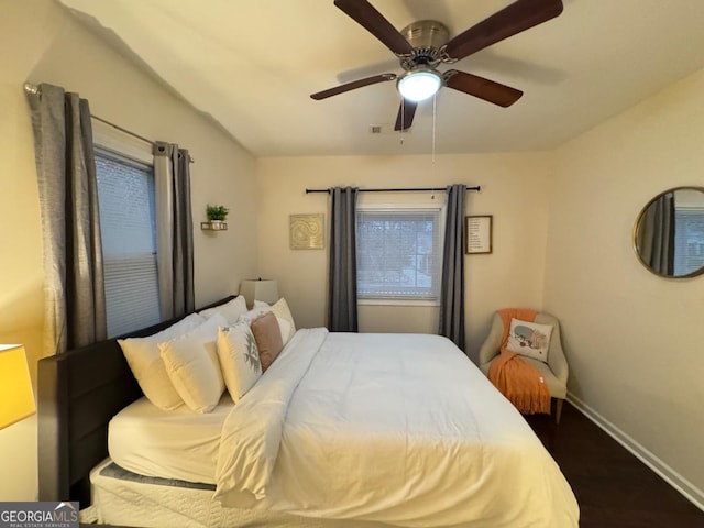 bedroom featuring visible vents, dark wood-style flooring, a ceiling fan, and baseboards