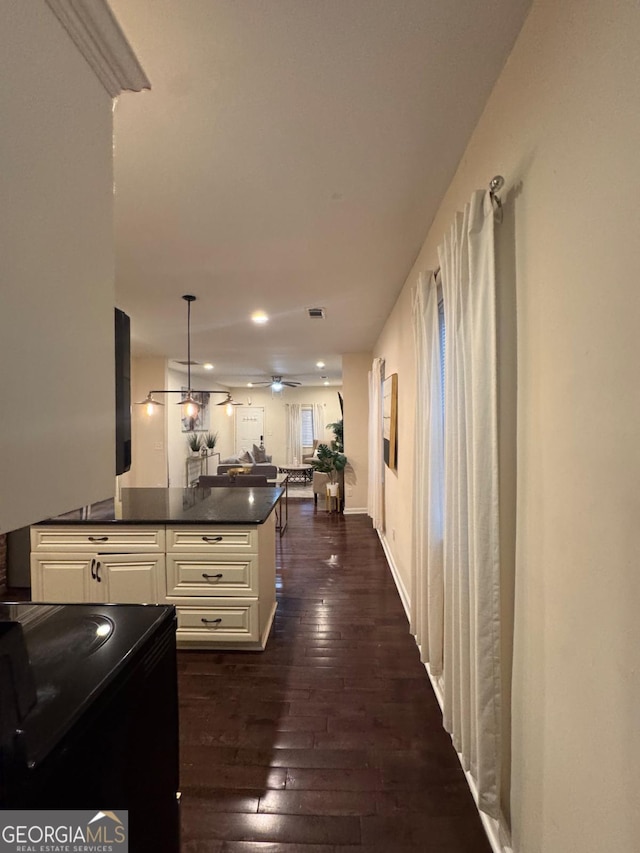 hall featuring dark wood finished floors, visible vents, and baseboards