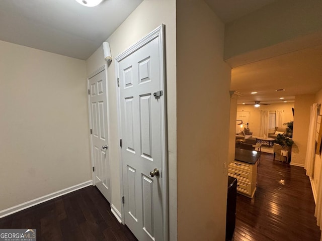 hallway with dark wood-style flooring and baseboards