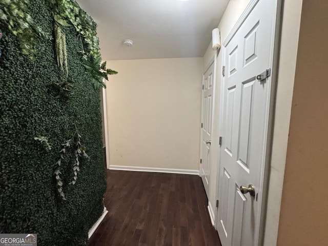 corridor with baseboards and wood finished floors