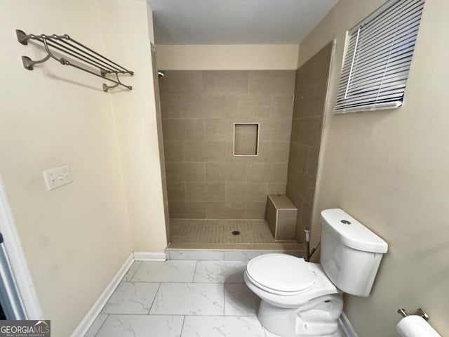 bathroom with marble finish floor, baseboards, a shower stall, and toilet