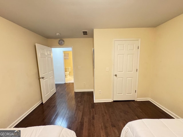 unfurnished bedroom with dark wood-style flooring, visible vents, and baseboards