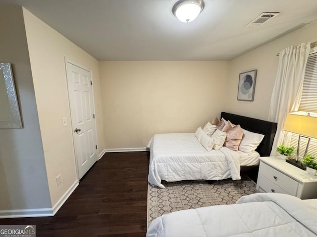 bedroom with wood finished floors, visible vents, and baseboards