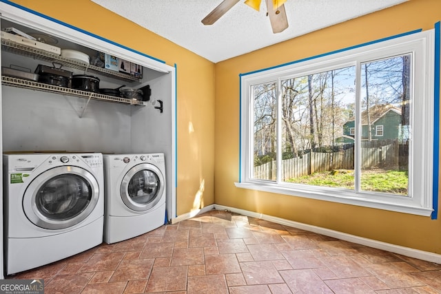 laundry room with washer and clothes dryer, stone finish flooring, a textured ceiling, and baseboards