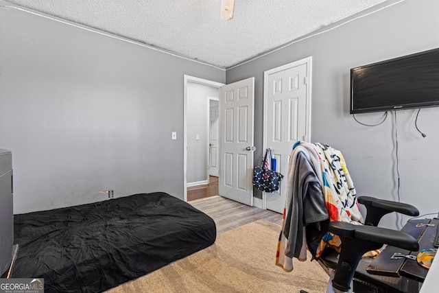 bedroom with a textured ceiling, a closet, and light wood-style floors