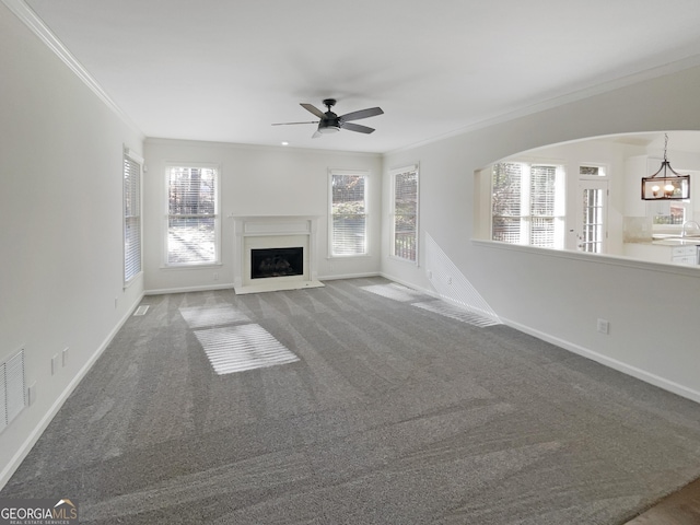 unfurnished living room featuring carpet, crown molding, a fireplace, and a wealth of natural light