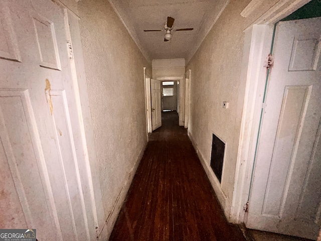 hallway with dark wood-style floors, visible vents, and a textured wall