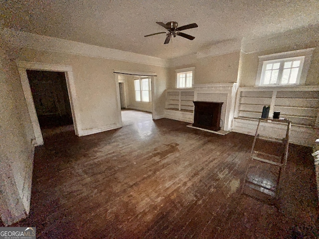 unfurnished living room featuring a fireplace with flush hearth, dark wood-style flooring, and a ceiling fan