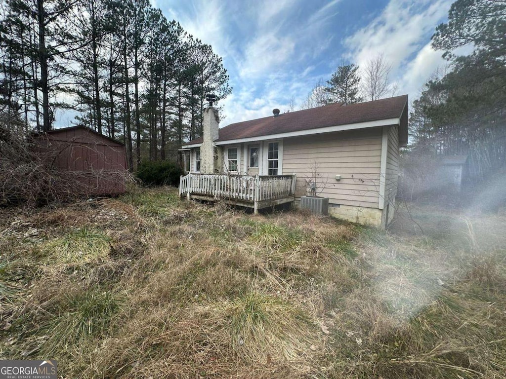 rear view of property featuring crawl space, a chimney, central AC unit, and a deck