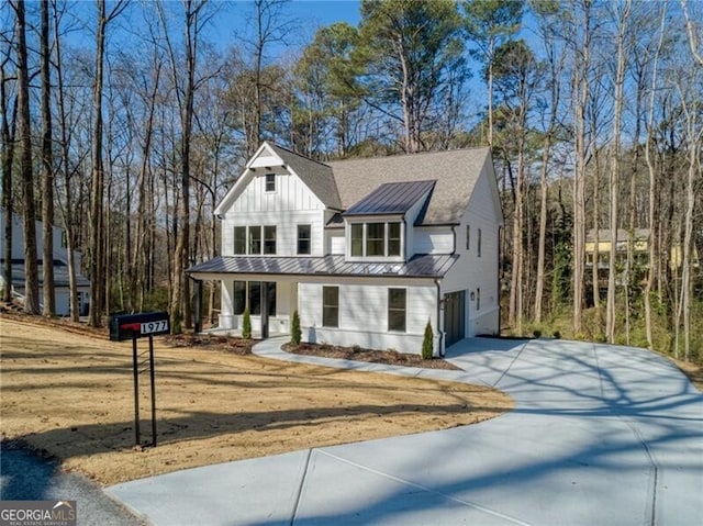 modern farmhouse with a porch, an attached garage, driveway, board and batten siding, and a standing seam roof