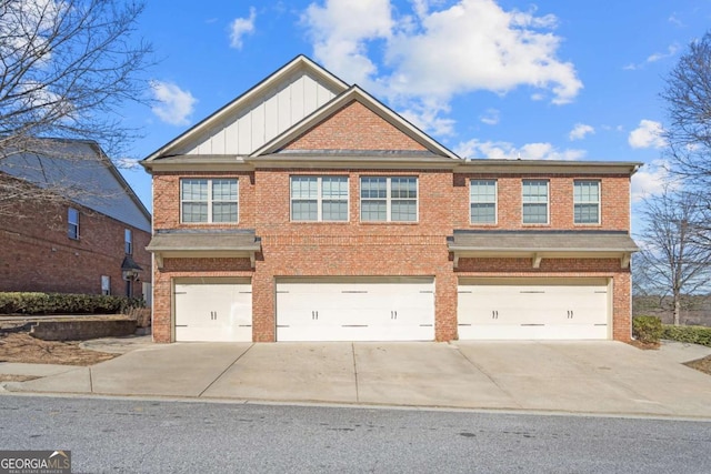 view of front of property with a garage, driveway, brick siding, and board and batten siding