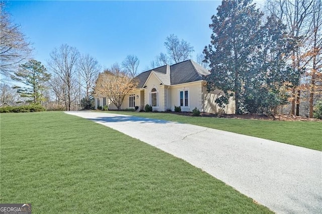 french provincial home featuring concrete driveway and a front yard