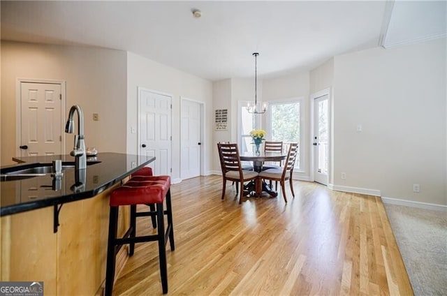 dining space featuring a chandelier, light wood-style flooring, and baseboards