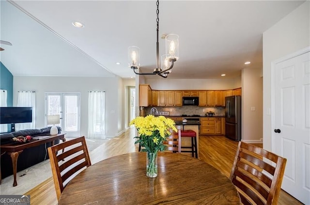 dining space featuring light wood-style floors, recessed lighting, a notable chandelier, and french doors