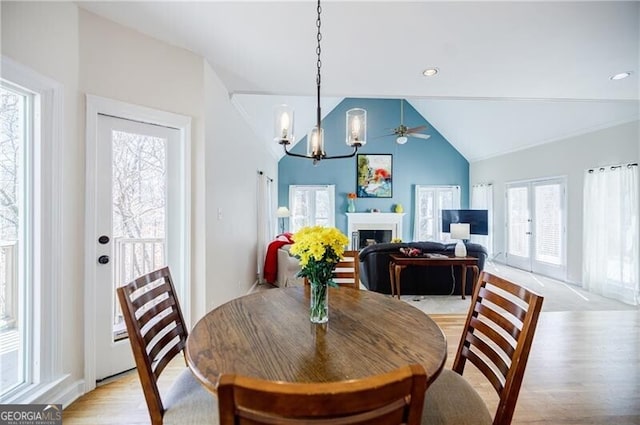 dining area featuring french doors, a fireplace, lofted ceiling, recessed lighting, and light wood-type flooring