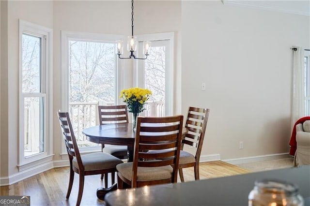 dining space featuring a chandelier, crown molding, baseboards, and wood finished floors