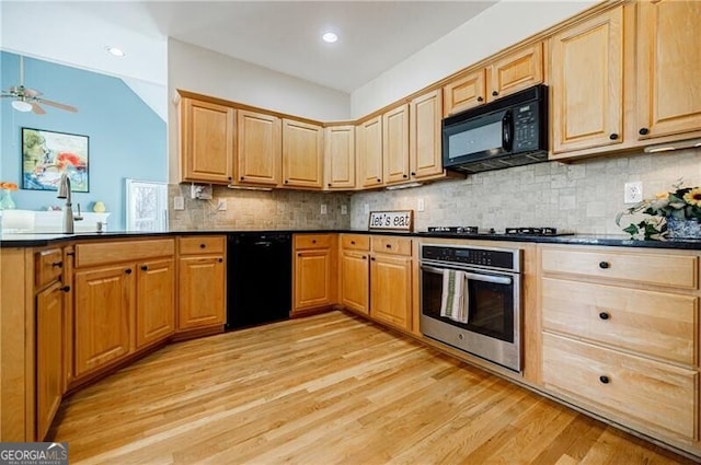 kitchen with light wood-style flooring, a peninsula, decorative backsplash, black appliances, and dark countertops