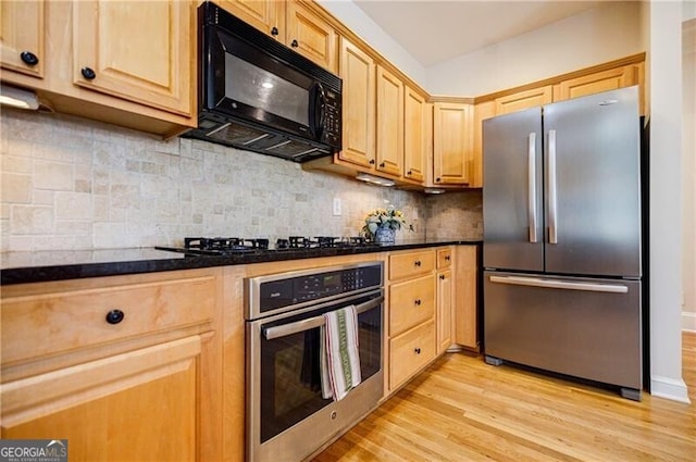 kitchen featuring black appliances, dark countertops, decorative backsplash, and light wood-style floors