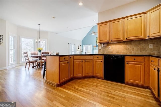 kitchen with dark countertops, black dishwasher, a sink, and a peninsula