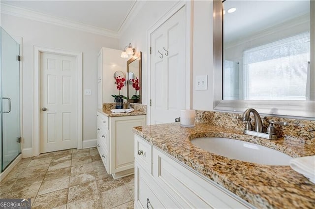 full bath featuring a shower stall, ornamental molding, two vanities, and a sink