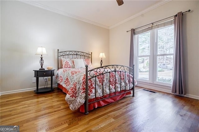 bedroom with visible vents, ornamental molding, a ceiling fan, wood finished floors, and baseboards