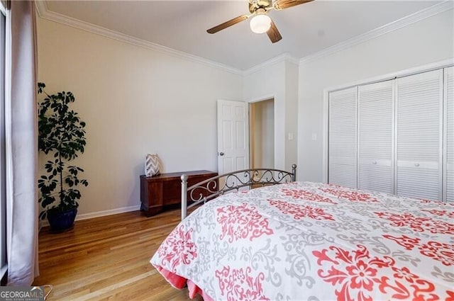 bedroom with a closet, light wood-style floors, ornamental molding, ceiling fan, and baseboards