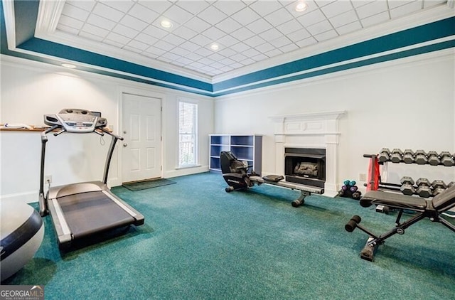 workout area featuring a raised ceiling, carpet flooring, crown molding, and a fireplace