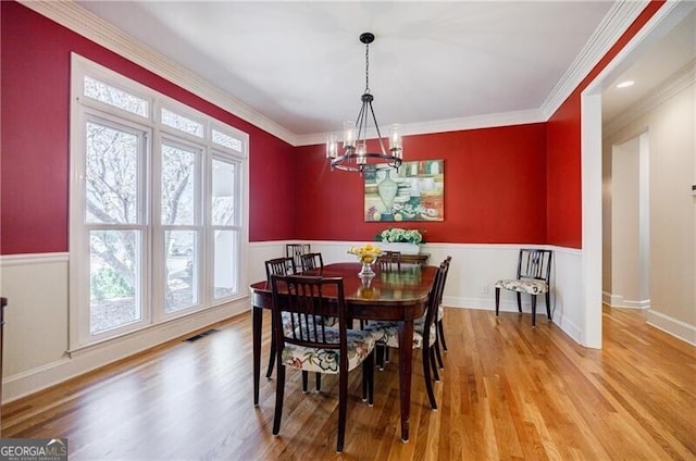 dining room with light wood-style floors, visible vents, crown molding, and an inviting chandelier