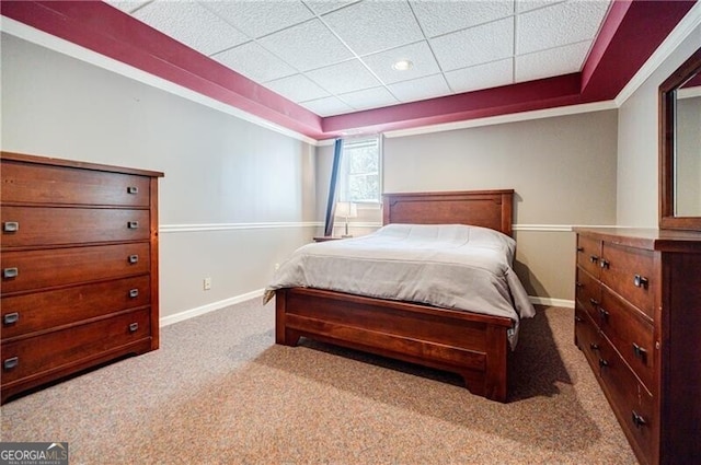 bedroom with a paneled ceiling, carpet, baseboards, and a raised ceiling