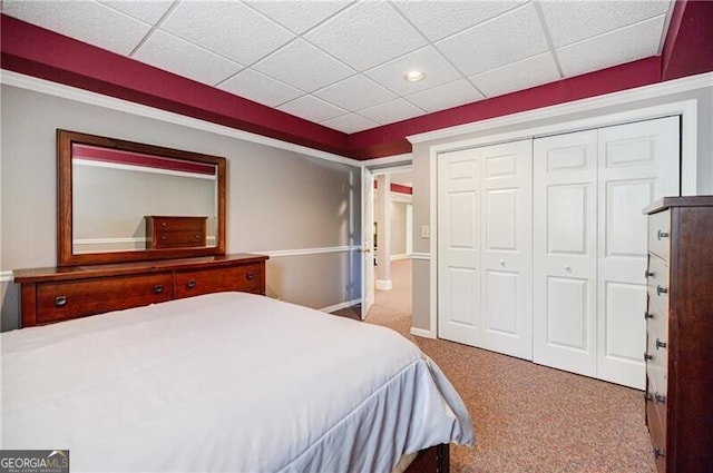 bedroom with a closet, carpet flooring, and a paneled ceiling