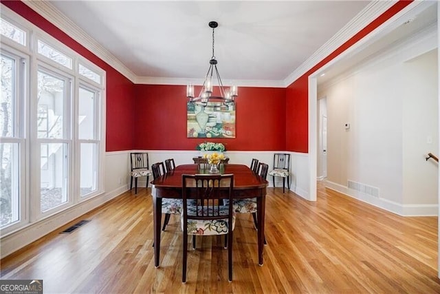 dining space featuring ornamental molding, visible vents, and light wood finished floors